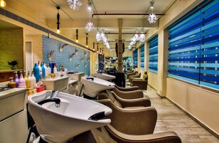 Une salle de bain d’hôtel avec plusieurs lavabos, des chaises et un grand miroir.