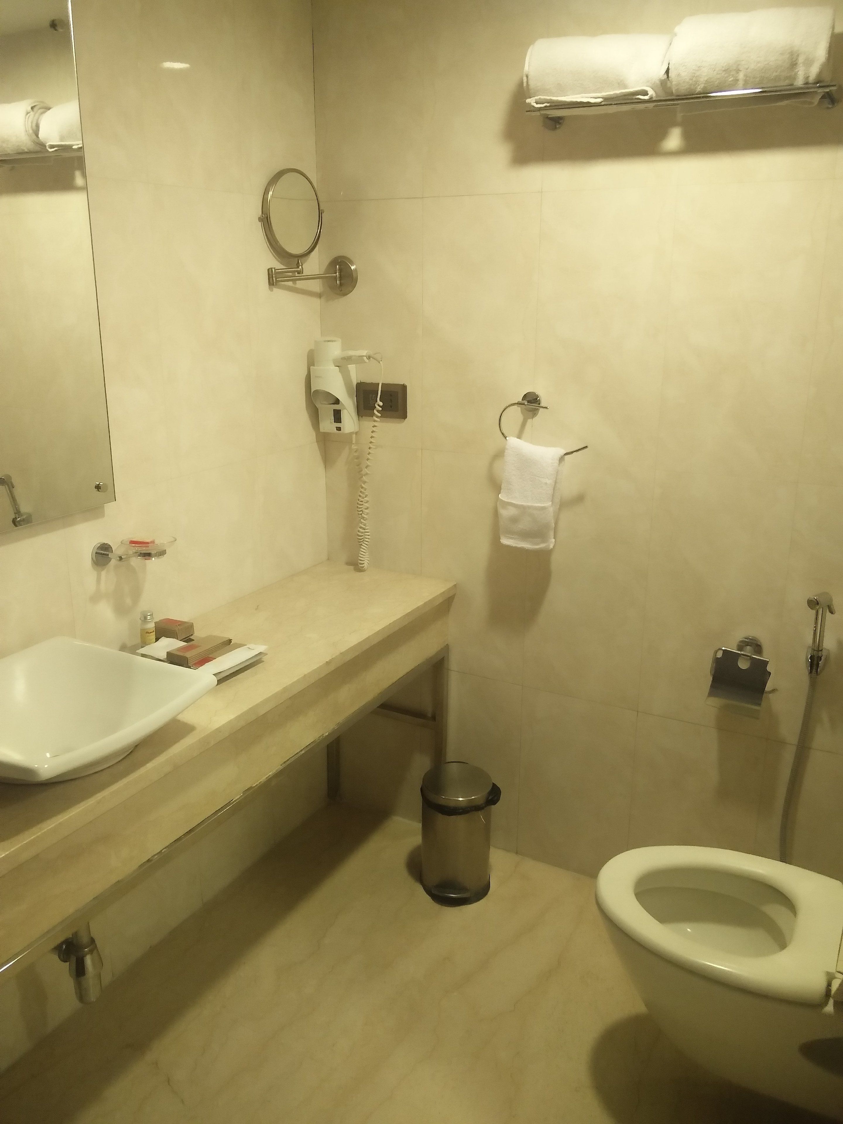 Un baño con lavabo, espejo, toallero, inodoro y cubo de basura.