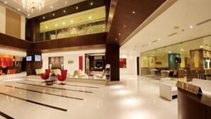 A spacious lobby with a modern design, featuring a reception desk, seating area with red chairs, and a glass partition. - Daspalla Hyderabad (Hyderabad)