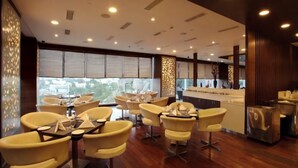 A modern interior with yellow chairs and tables, large windows, and a wooden floor. - Daspalla Hyderabad (Hyderabad)