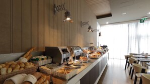 Un bufé de desayuno con panes, bollería y una estación de café.