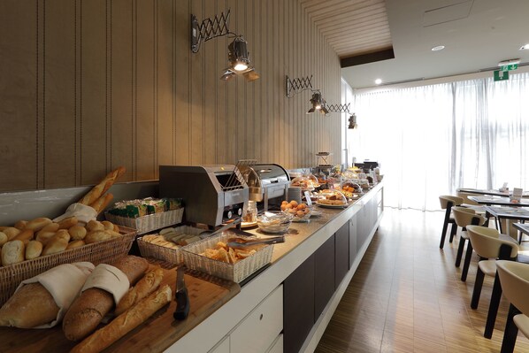 A breakfast buffet with various breads, pastries, and a coffee station. - Best Western Premier CHC Airport (Genoa)