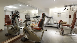 A gym with cardio machines, weightlifting equipment, and a mirrored wall.