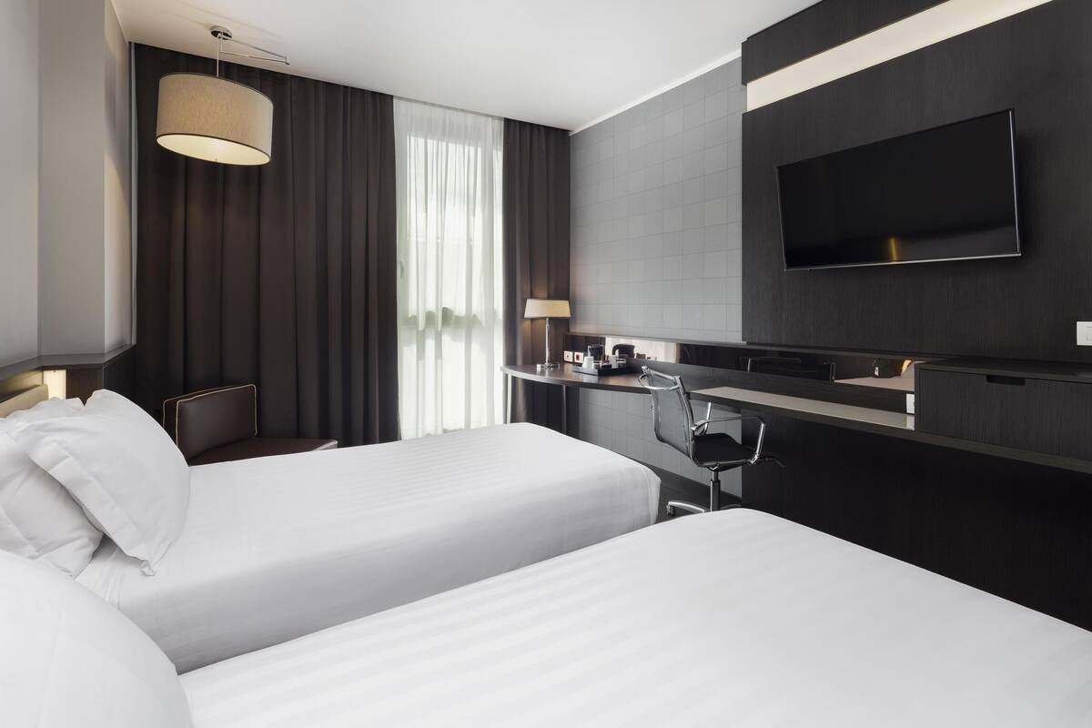 Een hotelkamer met twee bedden, een flatscreen televisie, een bureau en een stoel.