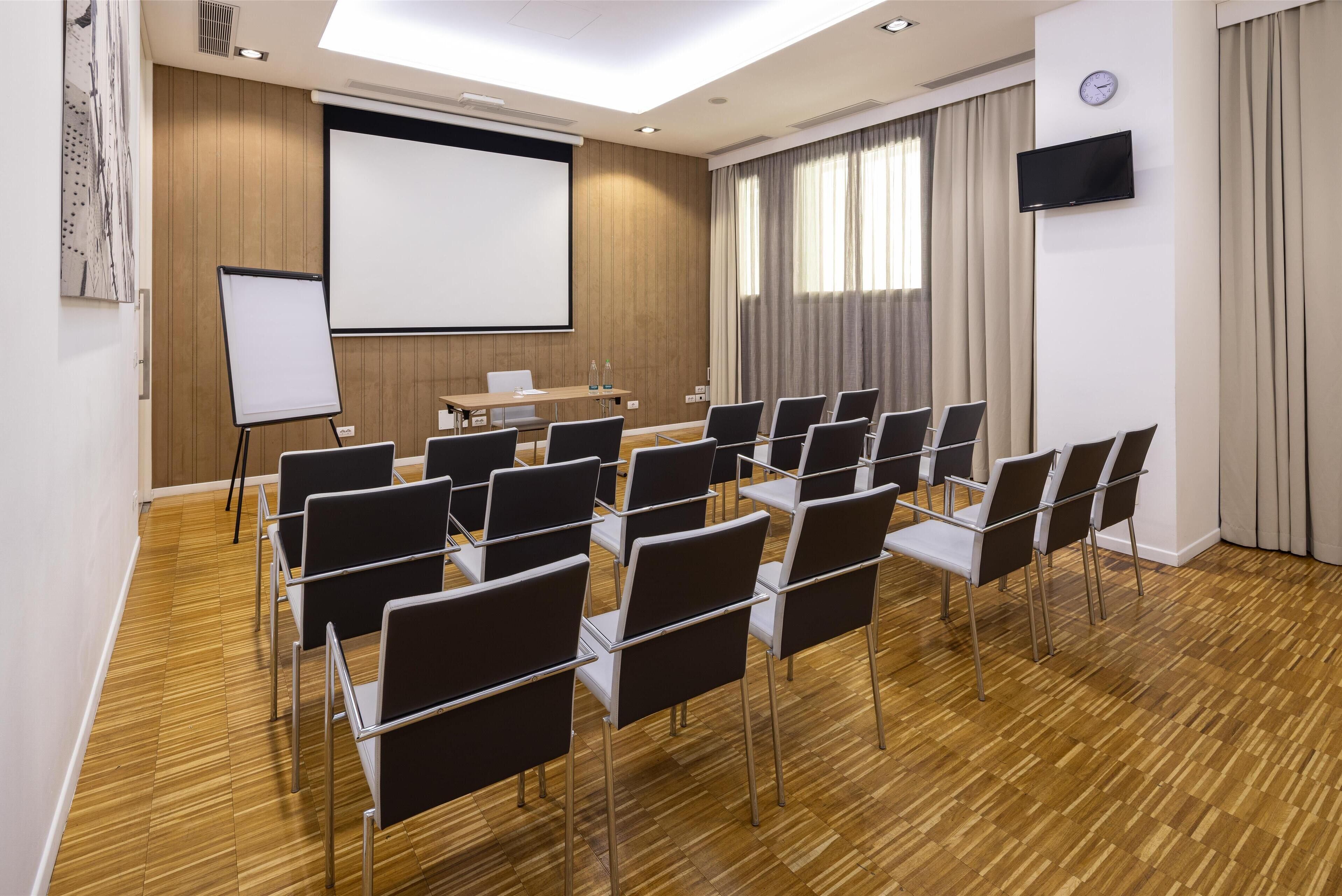 A conference room with a whiteboard, projector screen, and a long table with chairs.