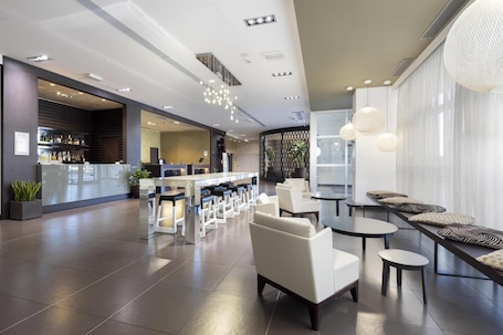 A modern hotel lobby with a bar area, seating arrangements, and a reception desk.