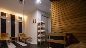 A sauna room with wooden benches, a glass partition, and a shelf with towels.