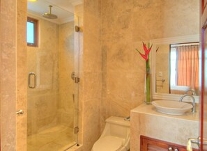 Une salle de bain avec une douche à parois de verre, des toilettes et un lavabo avec un miroir au-dessus.