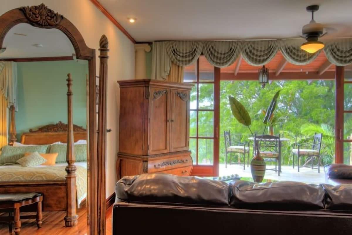 A bedroom with a four-poster bed, a wooden cabinet, and a sofa.