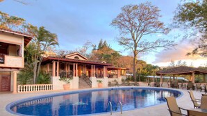 A swimming pool with lounge chairs and a covered patio area. - Ringle Resort & Spa (Escazu)