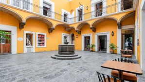 A courtyard with a fountain, outdoor seating, and arches. - Ayenda Meson de San Sebastian (Puebla)