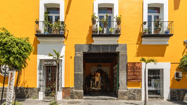 A yellow building with a storefront labeled "Resto" and a sign for "Hotel de San Juan." - Ayenda Meson de San Sebastian (Puebla)
