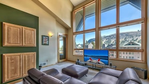 A living room with a large window, leather sofas, and a flat-screen TV. - Kirkwood Mountain Resort by Vail Resorts (Kirkwood)