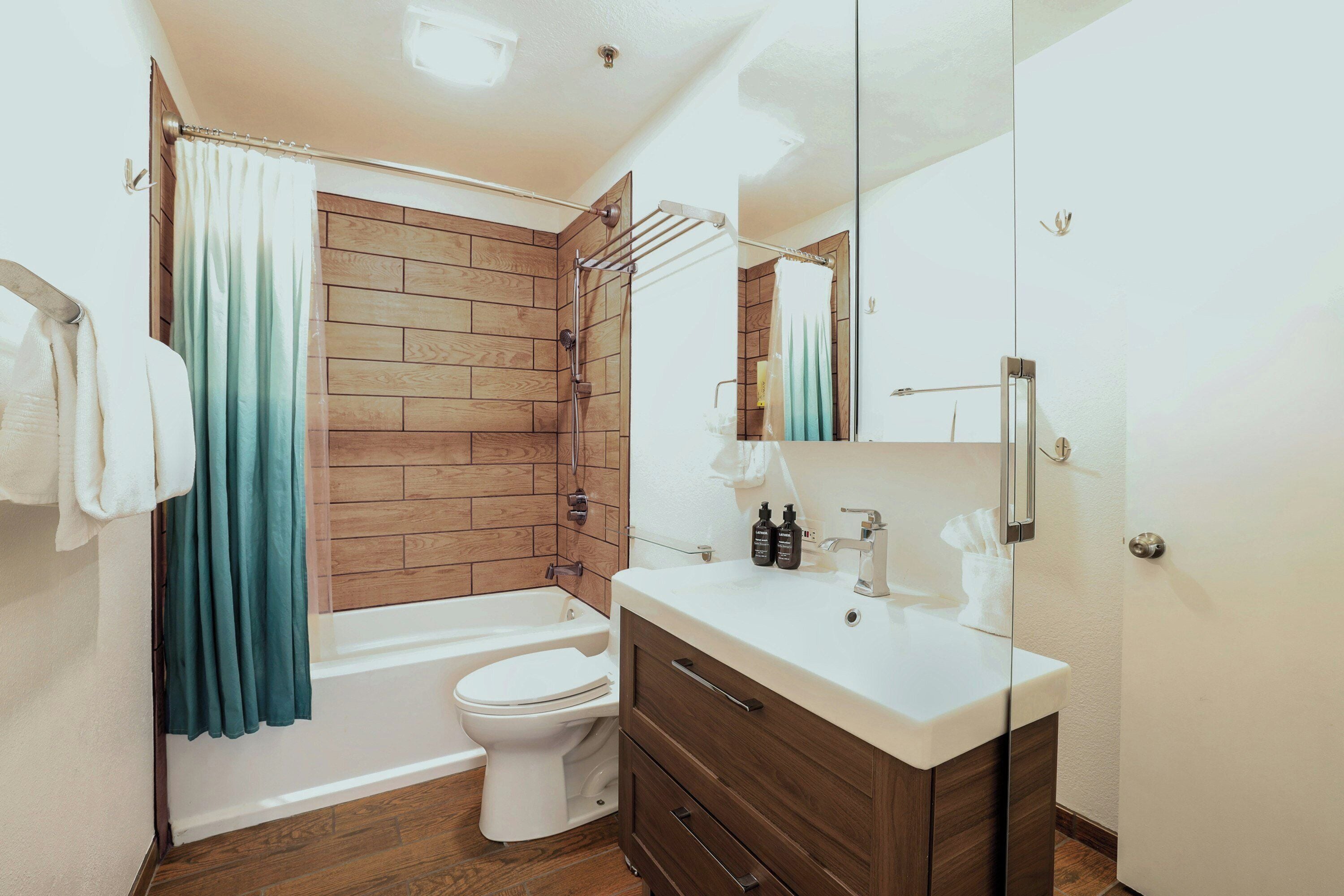 Un baño moderno con cabina de ducha de madera, inodoro blanco y tocador con espejo.