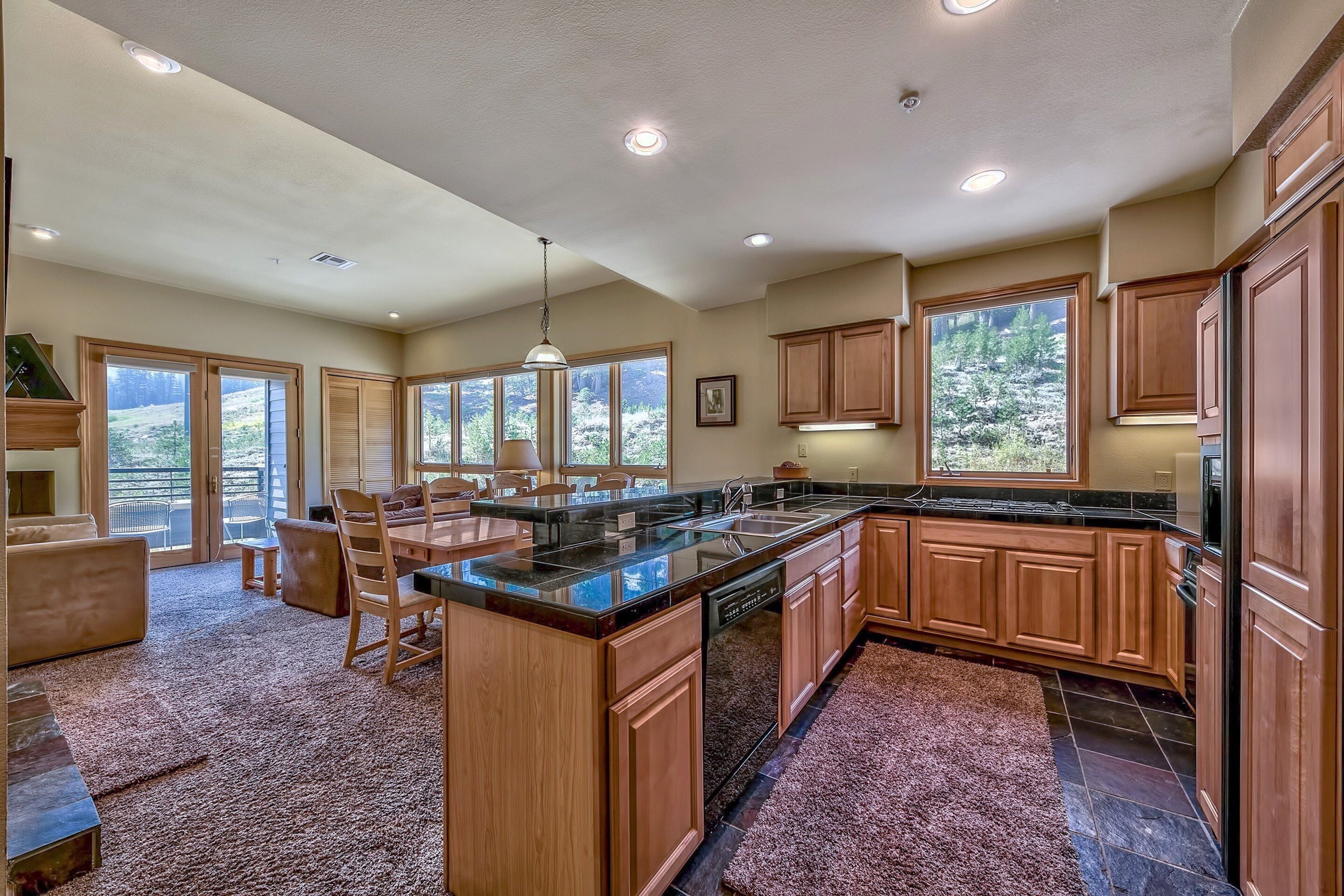 A spacious kitchen with wooden cabinets, a large island, and a view of the outdoors through the windows.