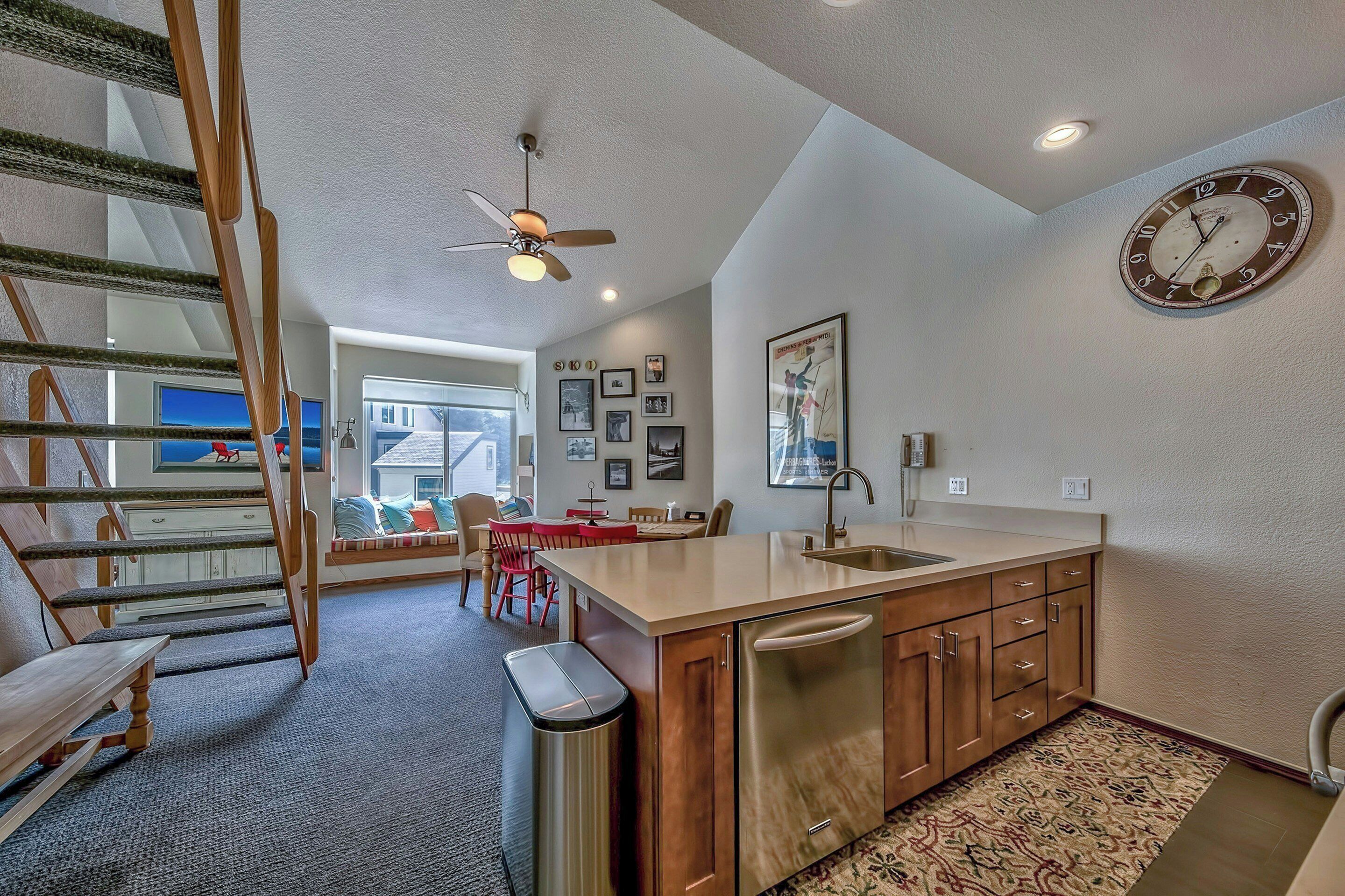 A kitchen with a wooden countertop, stainless steel appliances, a clock, and a ceiling fan.