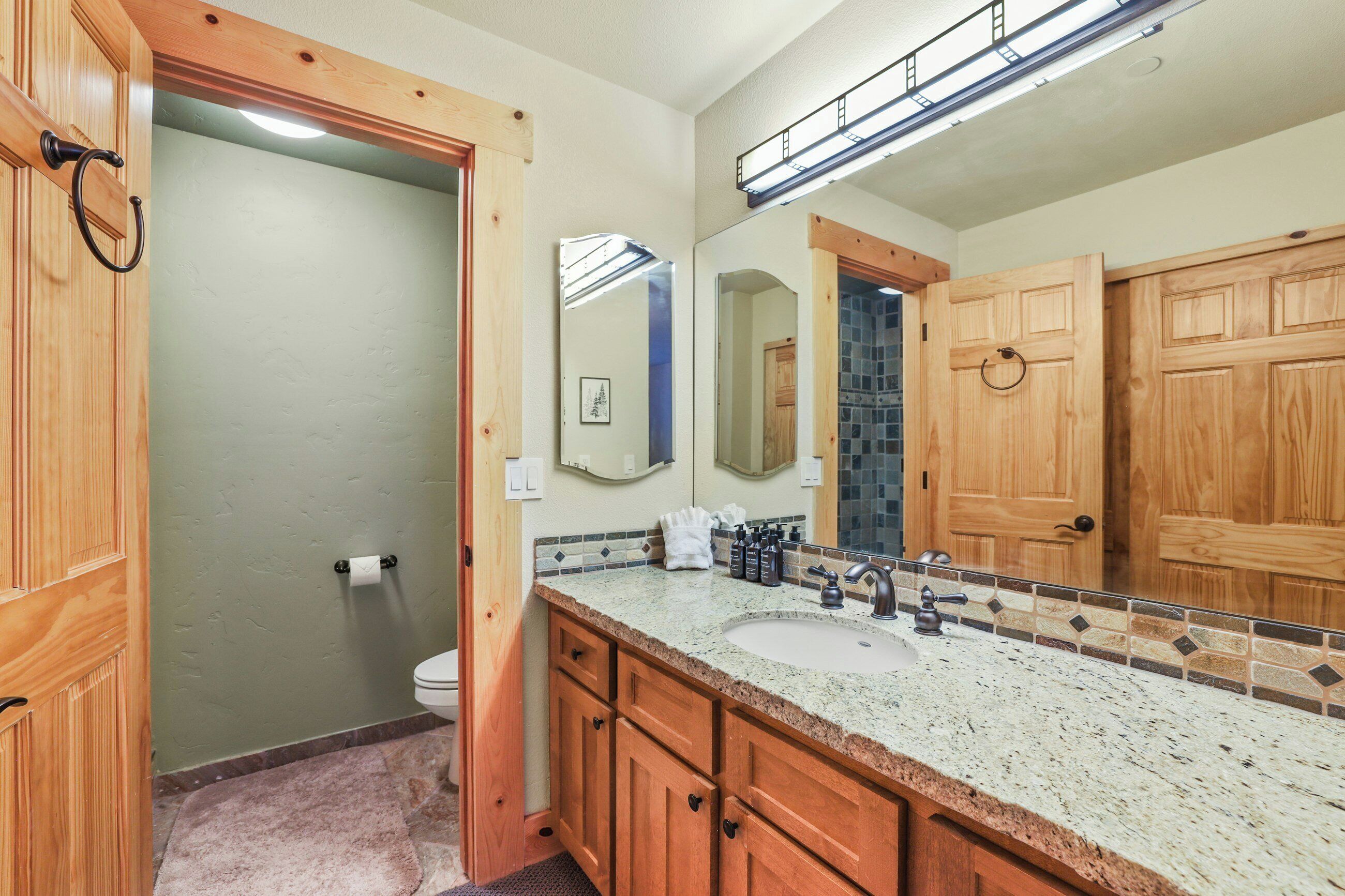 A bathroom with wooden cabinets, a sink, and a large mirror.