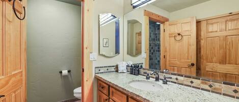 A bathroom with wooden cabinets, a sink, and a large mirror.