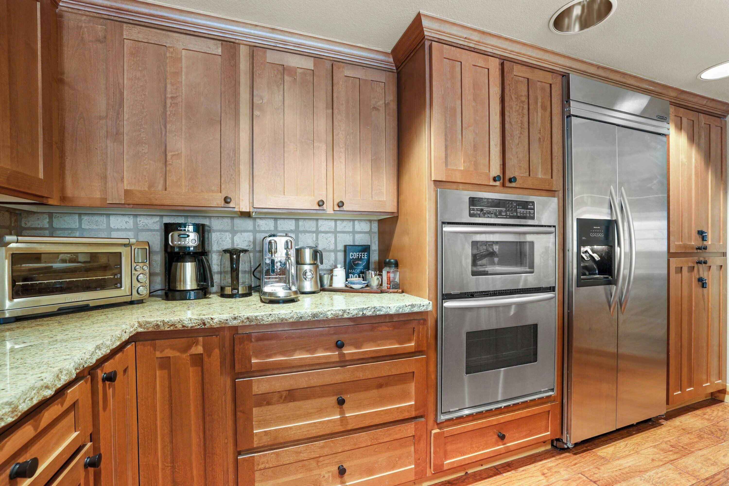 A kitchen with wooden cabinets, stainless steel appliances, and a granite countertop.