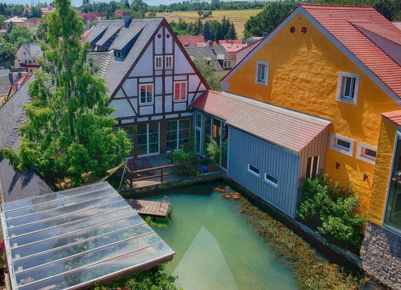 Un barrio residencial con casas tradicionales, un estanque pequeño y una terraza de madera.