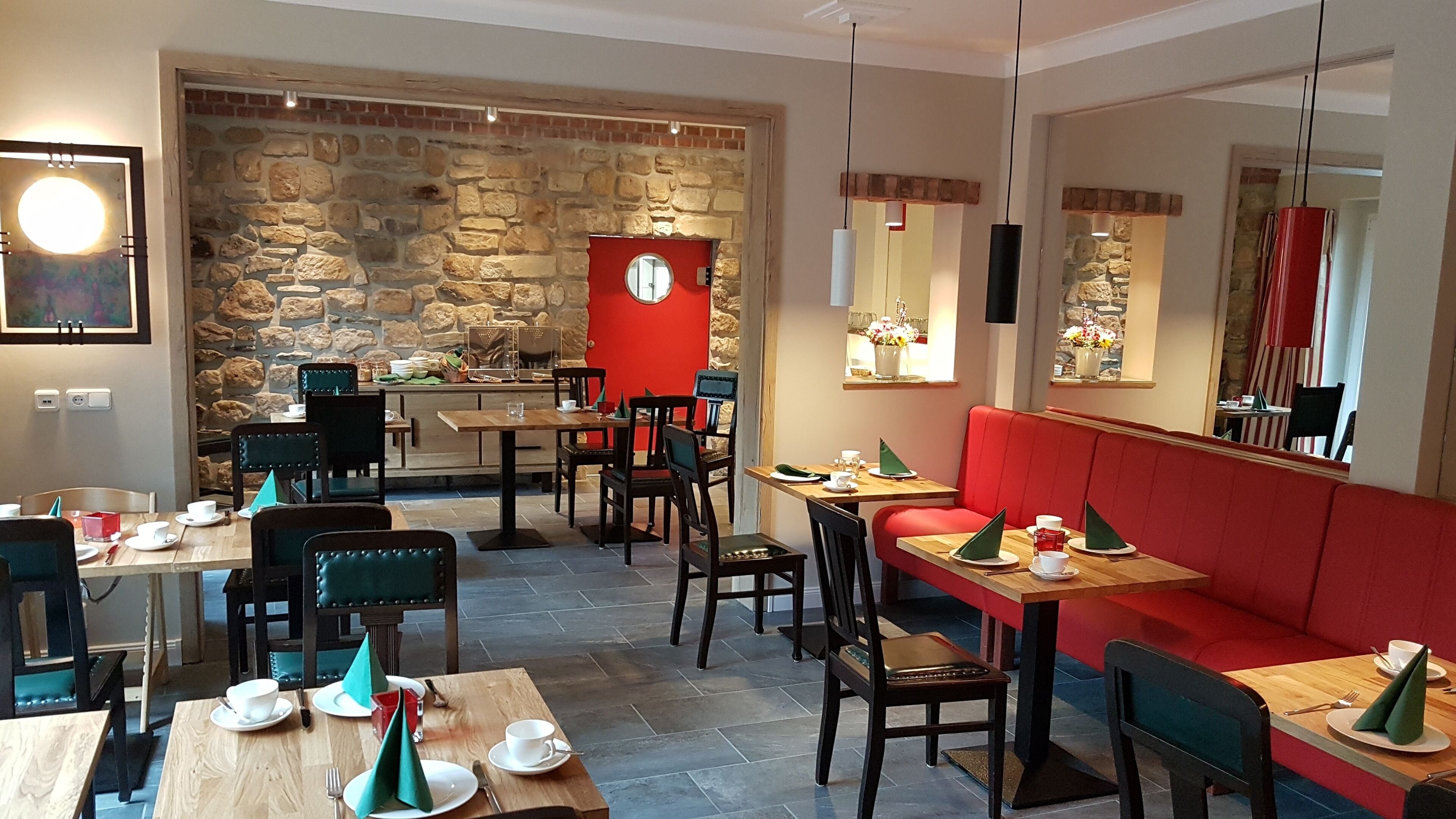Ein Restaurant mit Stehwänden, Holztischen und roten Sitzgelegenheiten.