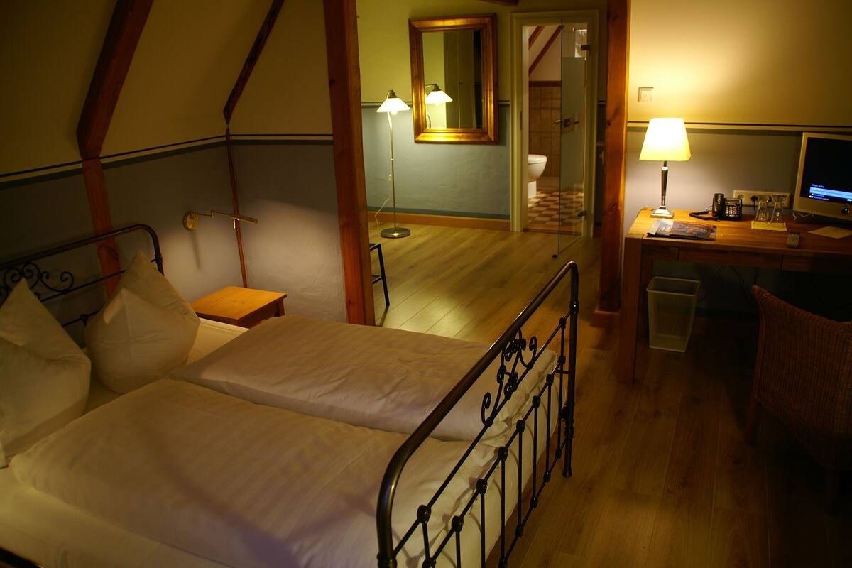 A bedroom with two beds, a desk with a computer, a lamp, and a mirror.