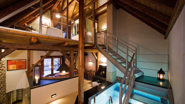 A multi-level interior with a wooden staircase, a fireplace, and a view of the outdoors.