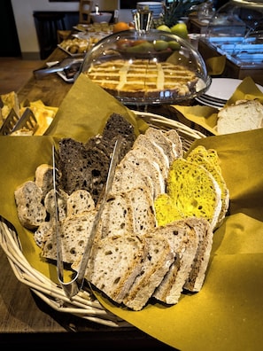 A buffet table with various breads and a covered dessert. - Le Mandrie di Ripalta (Montespertoli)