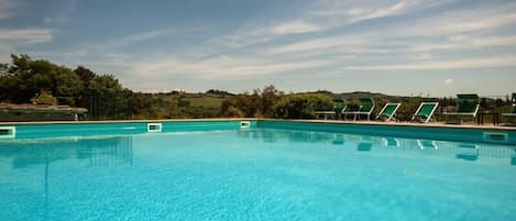 Una piscina al aire libre, sillones reclinables de piscina