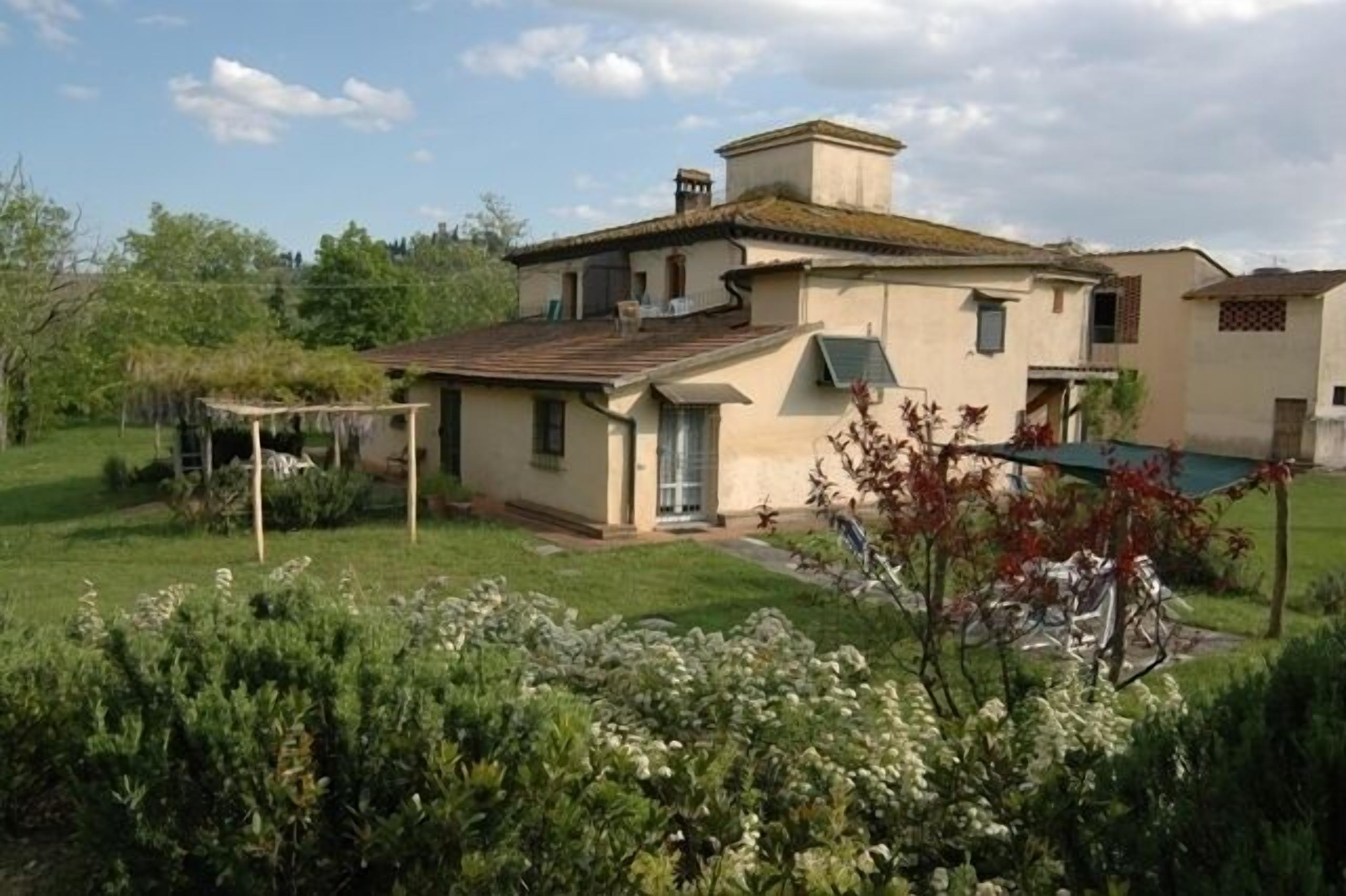 Una casa de dos pisos con techo inclinado, un pequeño porche y un jardín bien cuidado.