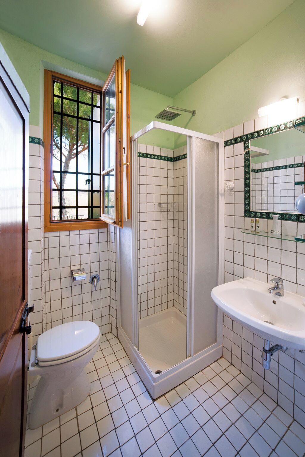 Un baño con inodoro, cabina de ducha y lavamanos.