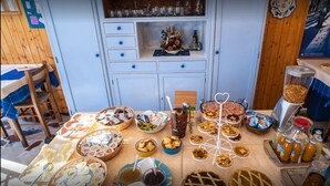 A dining area with a variety of food items, including pies, pastries, and condiments, arranged on a table. - Albergo Ristorante La Villa (Abetone Cutigliano)
