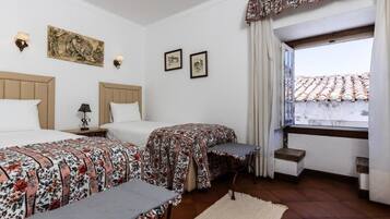 Una habitación de hotel con dos camas, una ventana con vistas y un pequeño balcón.