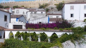 A historic town with white buildings, a fortified wall, and lush greenery. - Casa de S. Thiago do Castelo (Obidos)