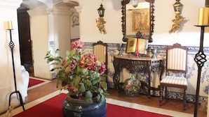 A room with a red carpet, a large potted plant, a mirror, and a table with chairs. - Casa de S. Thiago do Castelo (Obidos)