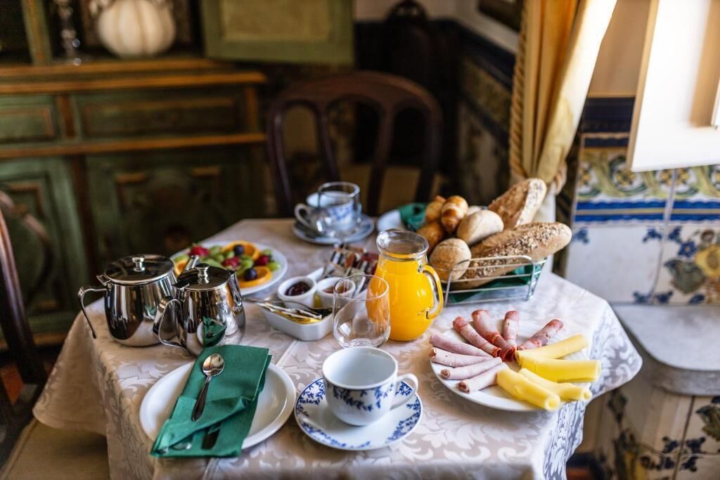 A breakfast table set with various food items, a pitcher of orange juice, and silverware.