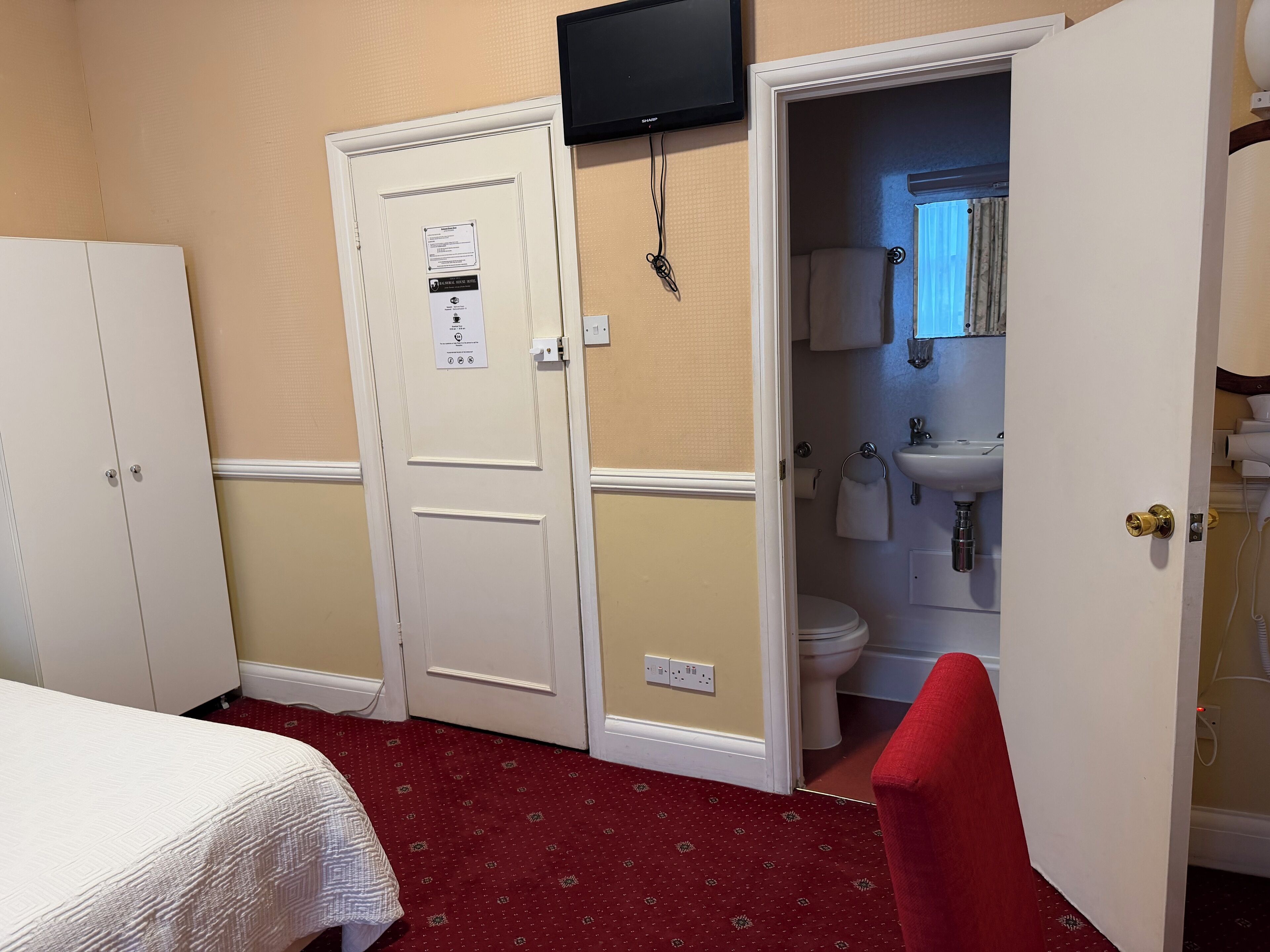 Ein Hotelzimmer mit Bett, Schrank und Badezimmer mit Toilette, Waschbecken und Spiegel.