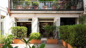 A courtyard with potted plants, a balcony with railings, and a building entrance. - La Castellana (Bergamo)