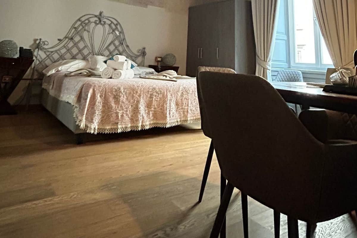 A room with a bed, a desk, and a chair. The ceiling has a decorative design.