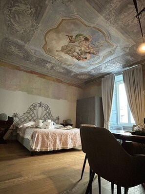 A room with a bed, a desk, and a chair. The ceiling has a decorative design. - La Castellana (Bergamo)