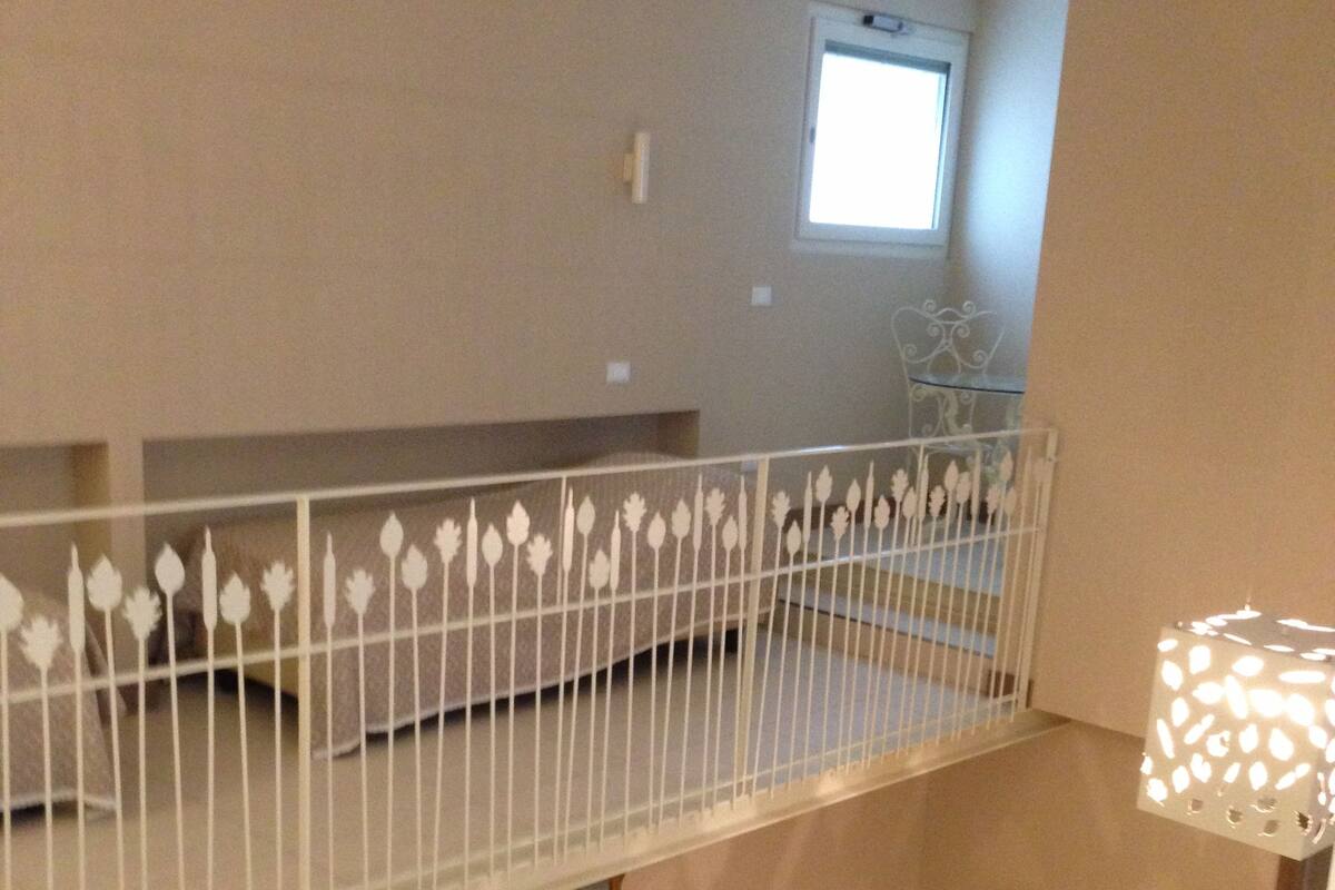 A room with a balcony, a small table with chairs, and a decorative railing.