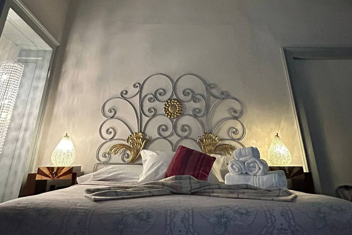 A bedroom with a bed, ornate ceiling, and two bedside lamps.