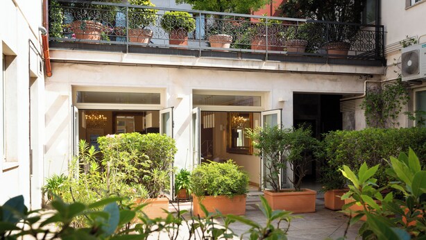 A courtyard with potted plants, a balcony with railings, and a building entrance. - La Castellana (Bergamo)