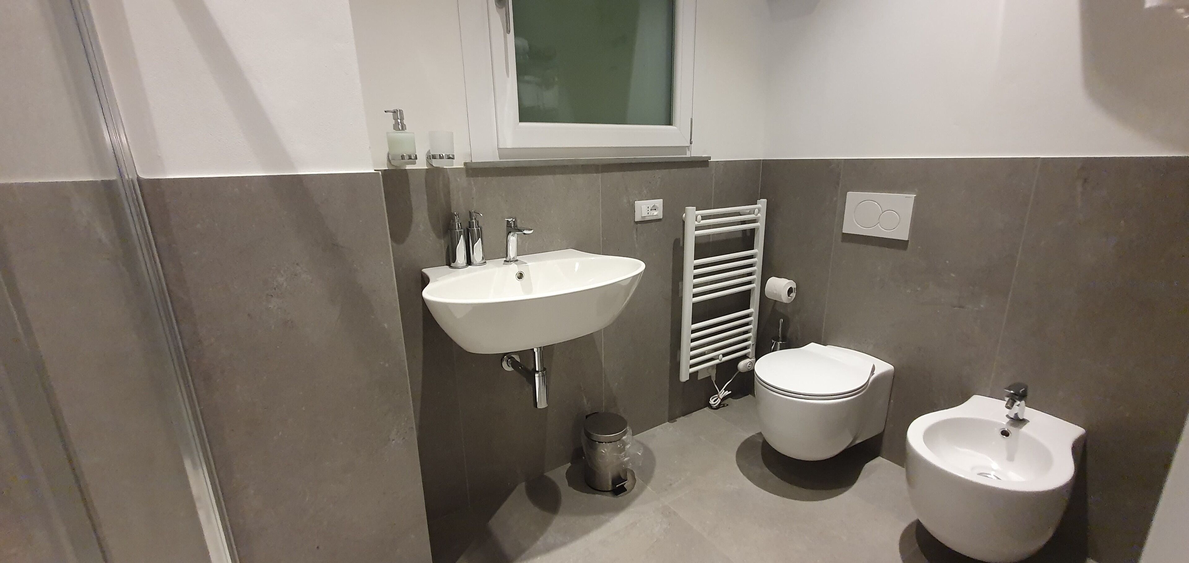 Une salle de bain moderne avec un lavabo blanc, des toilettes, un bidet et un porte-serviettes.