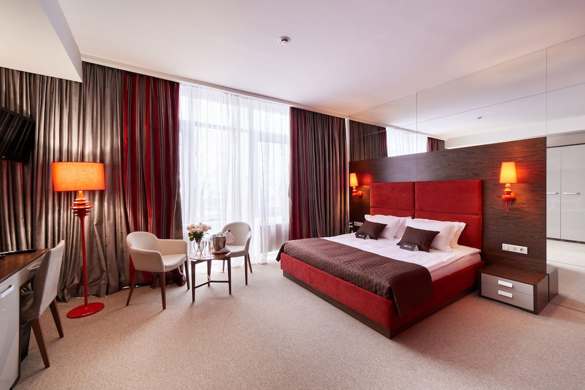 A modern hotel room with a large bed, a desk, and a chair.