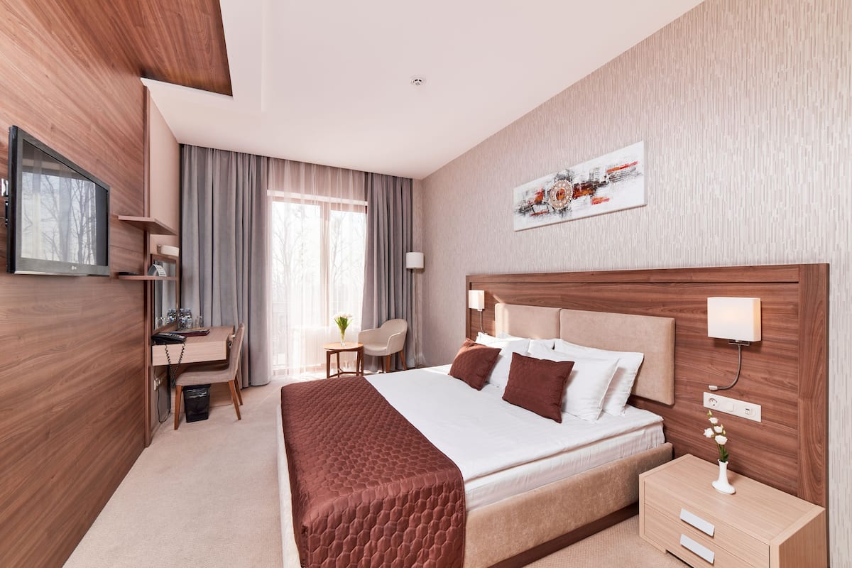 A modern hotel room with a large bed, a desk, and a television.