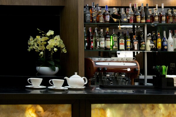 A bar area with a coffee machine, teapot, cups, and a variety of liquor bottles.