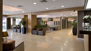 A spacious lobby with a reception desk, seating area, and a large chandelier.