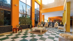 A lobby with a checkered floor, large windows, and a seating area with a coffee table and chairs. - Hotel Palmarena Plaza (Santa Marta)