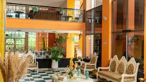 A hotel lobby with a checkered floor, a reception desk, seating area, and a balcony with plants. - Hotel Palmarena Plaza (Santa Marta)